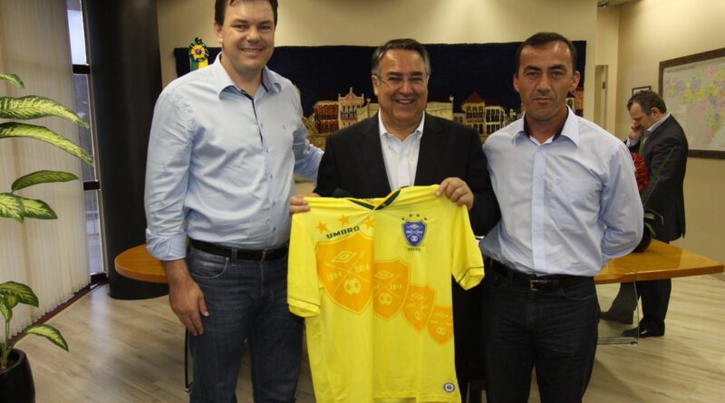 Por ocasião da assinatura do convênio do Fundam, o prefeito Daniel e o vice Sadan entregaram ao governador Colombo (c), como presente, uma camisa retrô da seleção brasileira de 94